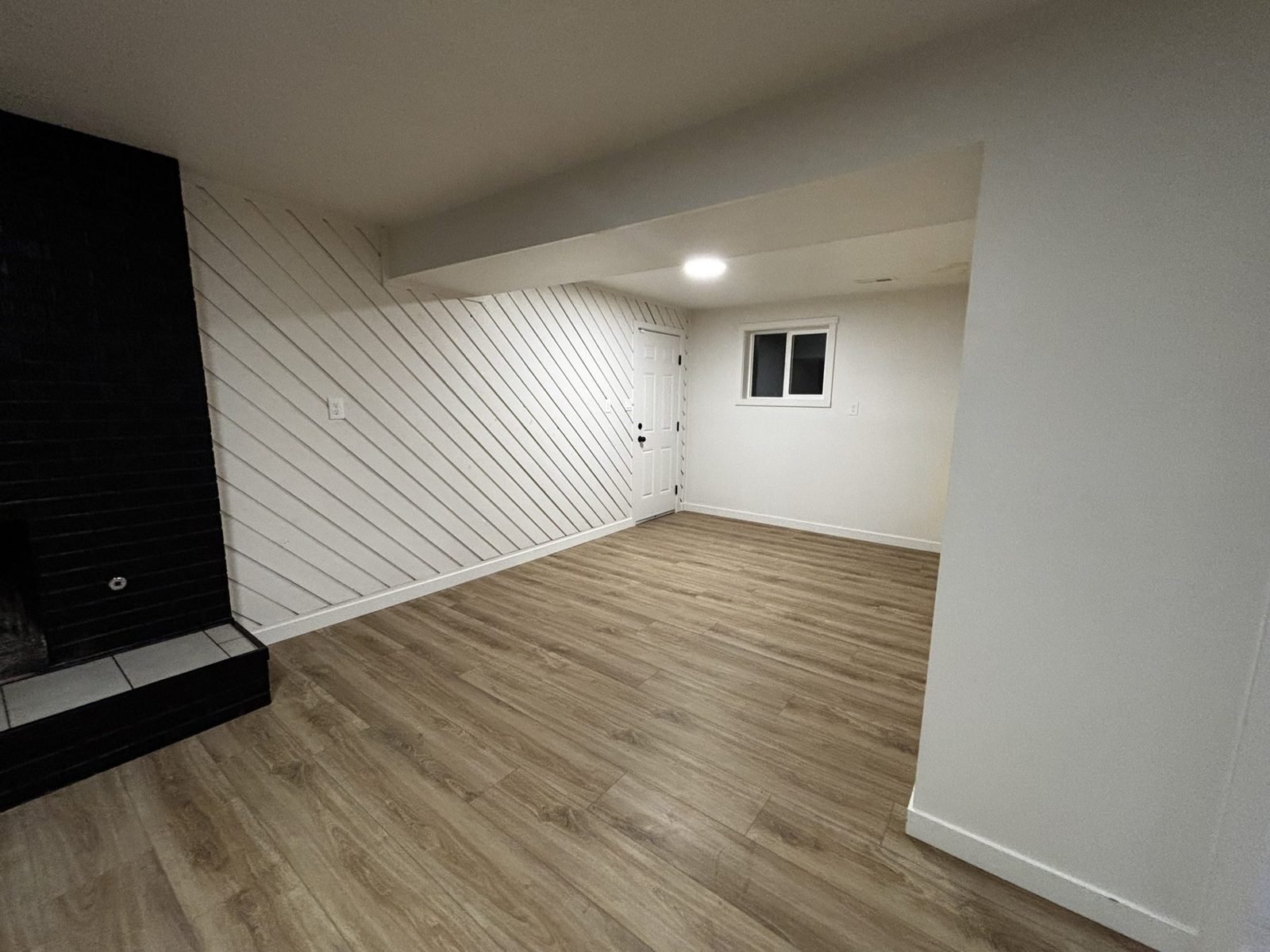 Finished basement family room with shiplap fireplace wall by Roots Finished Basements in Salem, Utah