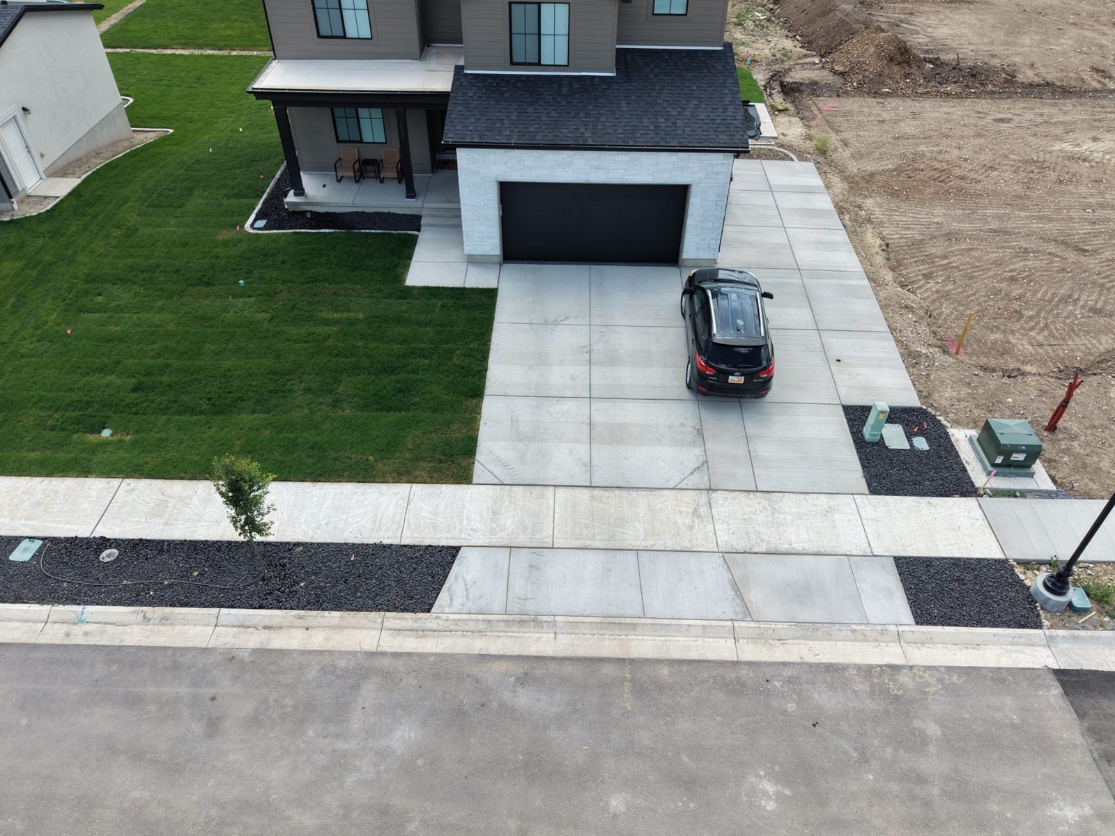 Drone photo of a finished new construction front yard with fresh sod and driveway by Roots Landscaping in south Utah County