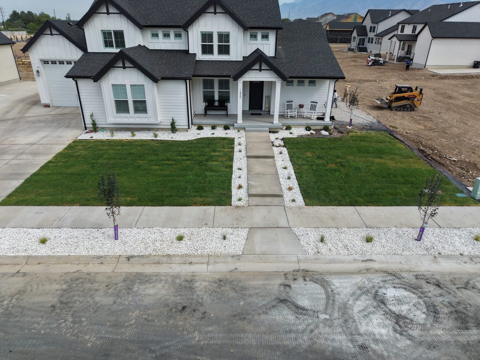 Finished front yard on a new construction home in south Utah County with sod, rock beds, trees and a concrete walk by Roots Landscaping